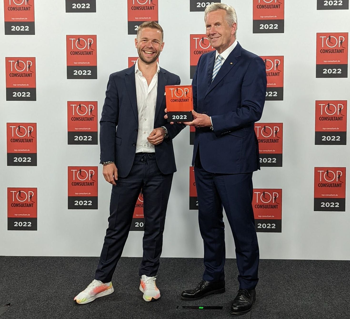 Men in suits hold up TOP CONSULTANT Award