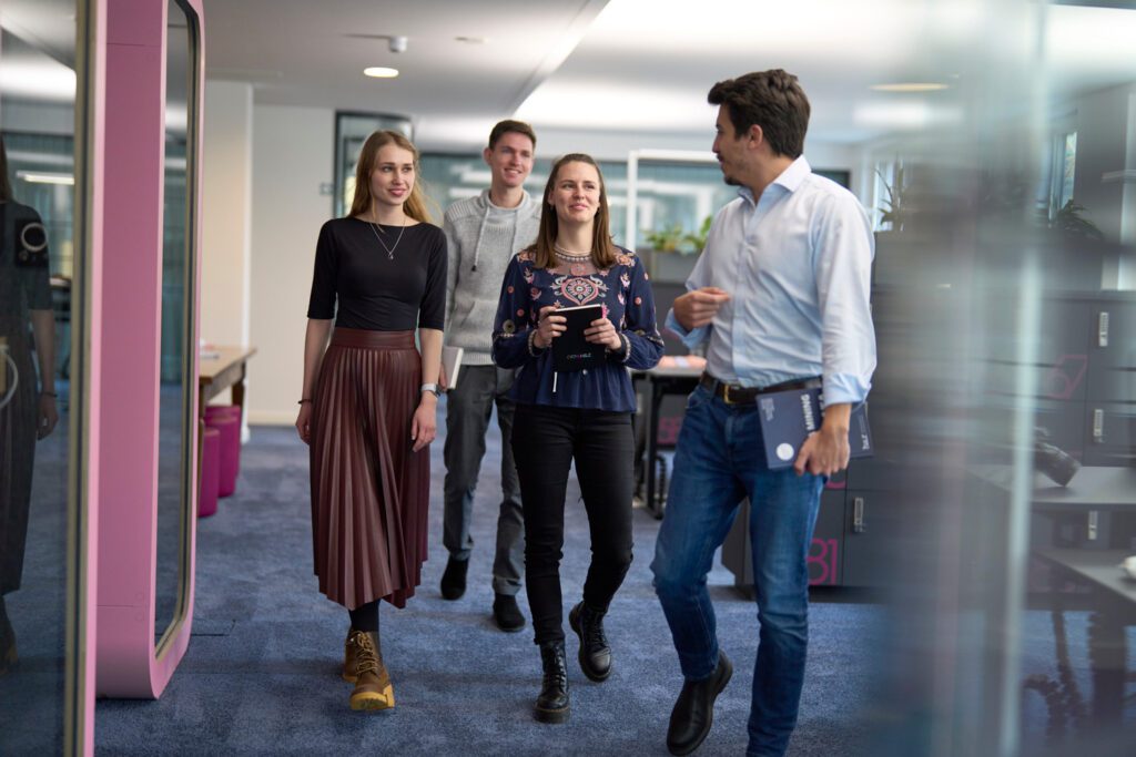 Group of young professionals walking and discussing ideas in a modern office representing collaborative consulting teamwork
