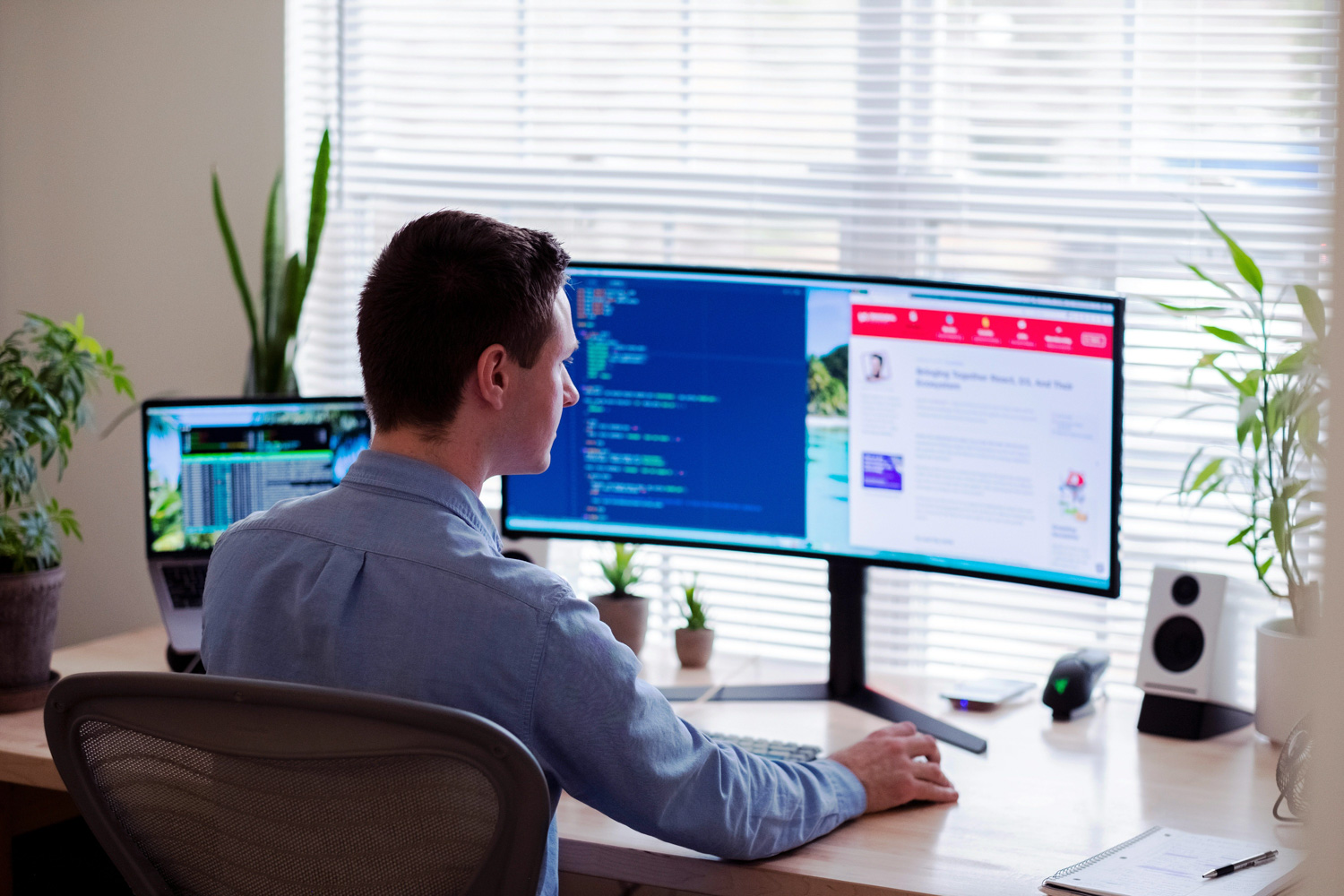Man working at a desk with dual computer monitors displaying analytics and code, representing H&Z consulting's data-driven approach to IT spending optimization.