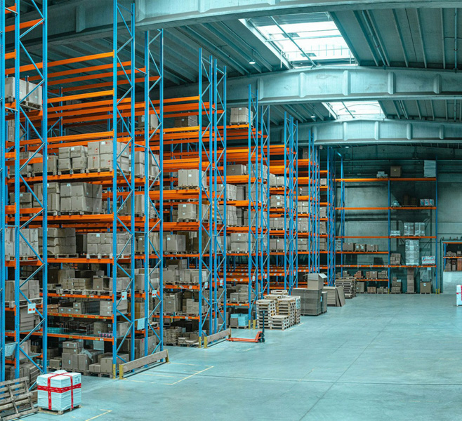 Large warehouse interior with blue and orange pallet racks stacked with boxes and crates – HZ Group consulting supply chain and logistics