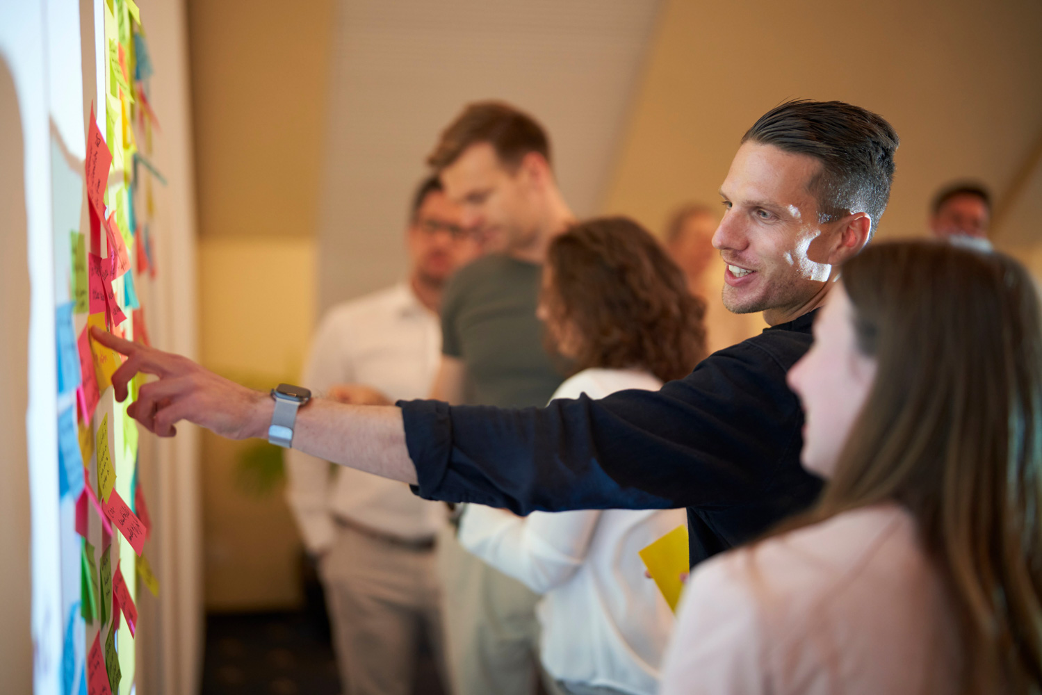H&Z consultants participating in a collaborative workshop, placing colorful sticky notes on a wall during a brainstorming session to generate innovative business ideas.