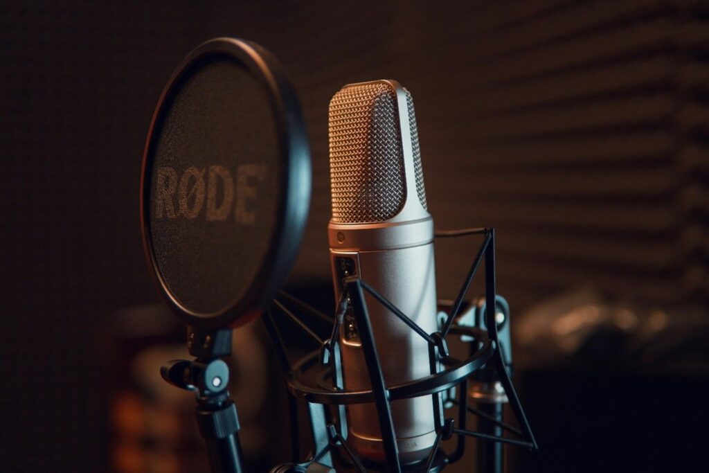 Close‑up of a RODE microphone with pop filter in a professional studio for podcast recording and consulting discussions
