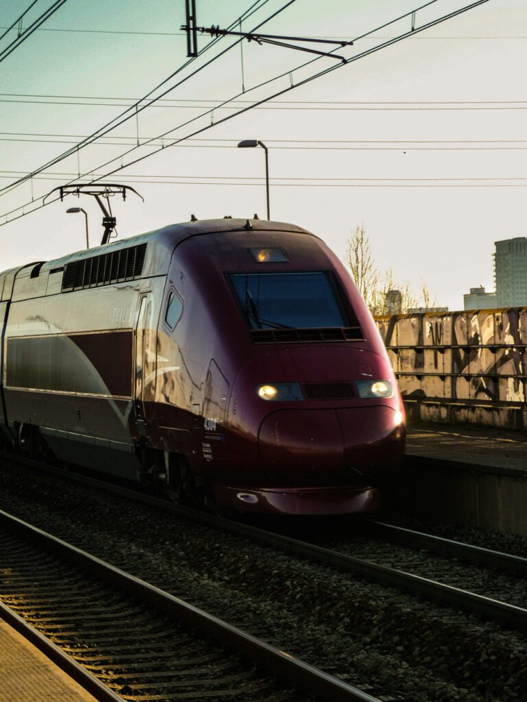 A sleek maroon high-speed passenger train traveling along electrified tracks, illustrating modern rail transport and price benchmarking of rail components in strategic procurement consulting.