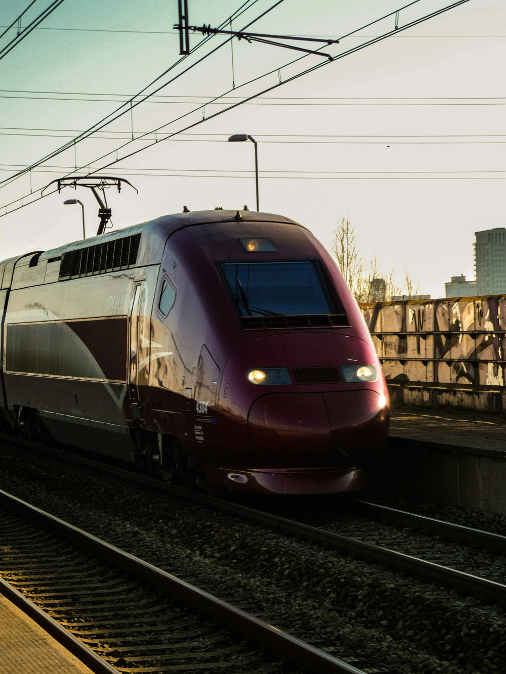 A sleek maroon high-speed passenger train traveling along electrified tracks, illustrating modern rail transport and price benchmarking of rail components in strategic procurement consulting.