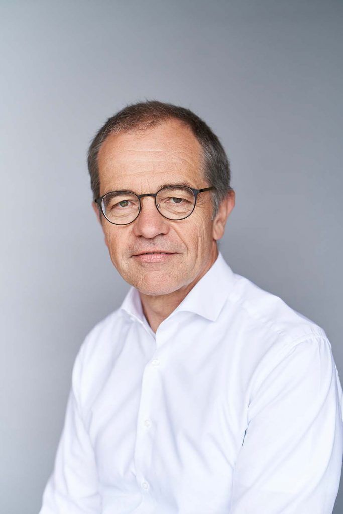 Portrait of senior consultant wearing glasses and a white shirt, exuding experience and strategic leadership in professional consulting services.