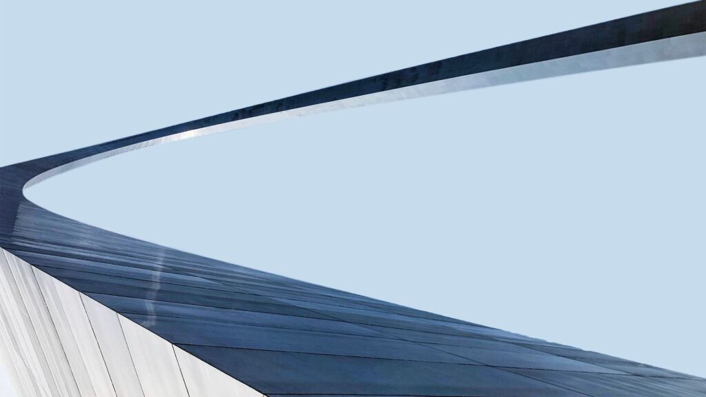 Abstract curved architectural structure with sweeping blue and white surfaces against a clear sky, symbolising modern performance management and agile methodologies in corporate consulting.