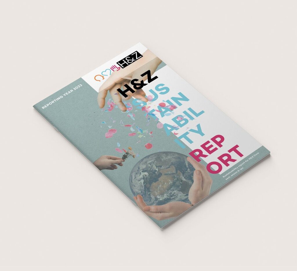 Angled view of H&Z sustainability report booklet featuring an Earth globe and confetti on a teal background, illustrating sustainability reporting and consulting services.