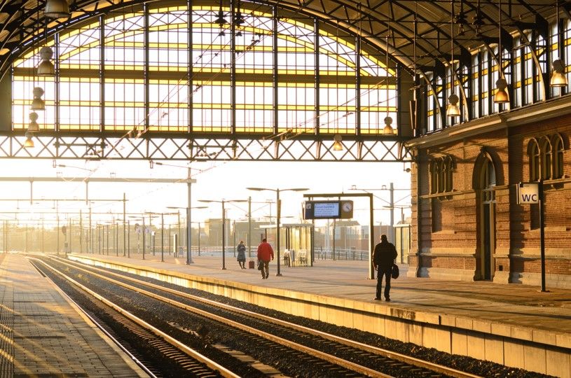 Vintage railway station platform bathed in golden sunlight with commuters, symbolizing transformation and journey in sales and project management consulting.