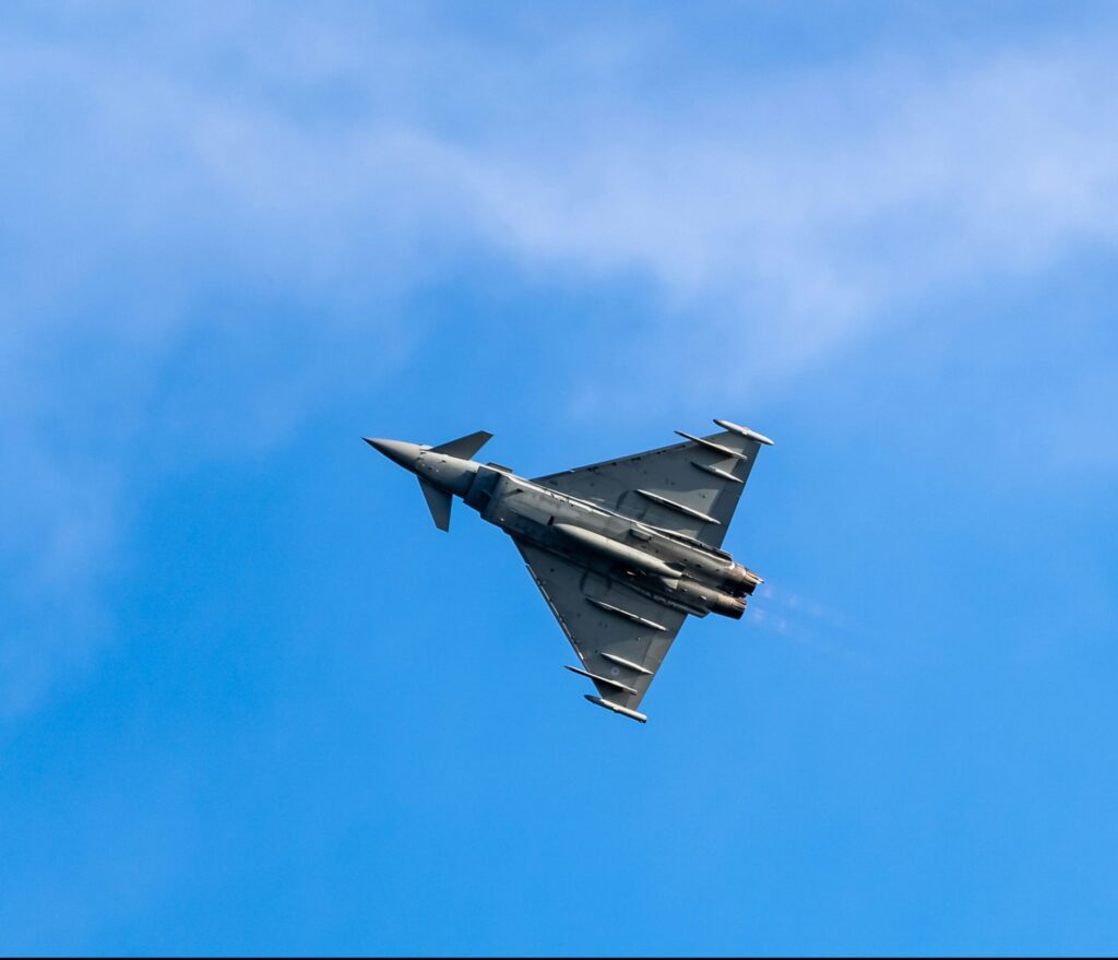 High-performance fighter jet soaring upward in a clear blue sky, symbolizing advanced technology and agility required in modern supply chain consulting.
