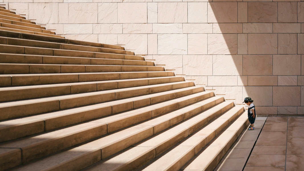 Person ascending modern stone stairs representing professional growth and progress