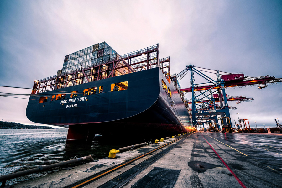 Large container ship docked at a port with cranes in the background – HZ Group consulting logistics and maritime operations