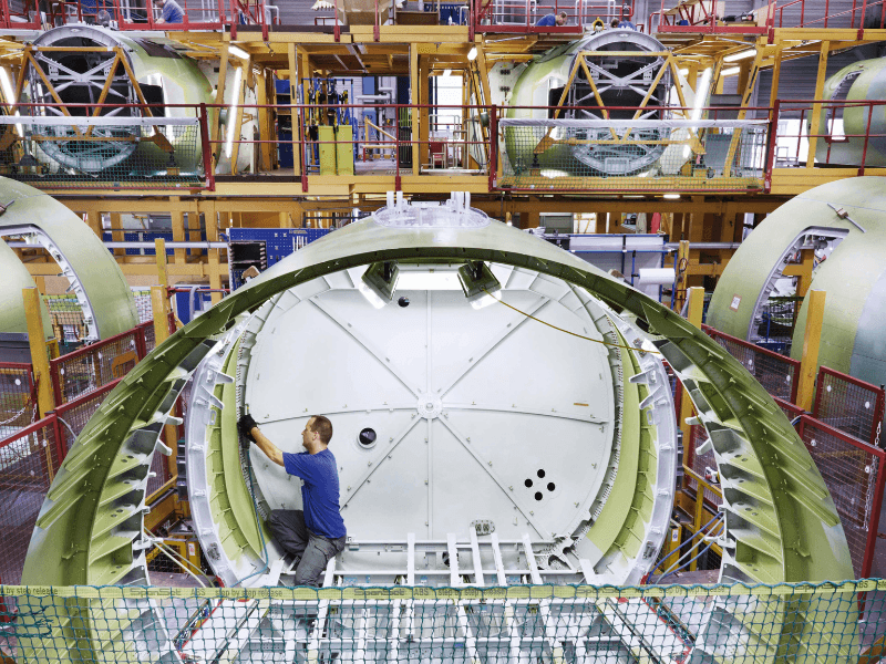 Technician assembling an aircraft fuselage section inside an aerospace manufacturing facility, highlighting precision engineering and industry expertise relevant to consulting services.