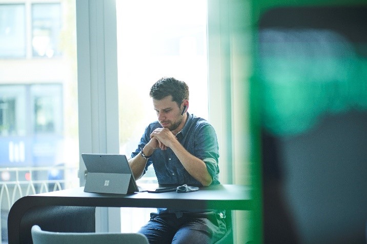 Man consulting professional working on a laptop with headphones in a modern cafe, representing remote work and business functions at H & Z consulting.