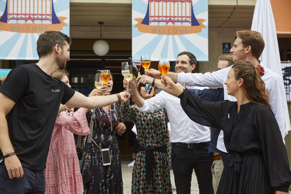 Team members raising glasses in a celebratory toast at an H&Z welcome event, illustrating camaraderie and celebration within the consulting firm culture.