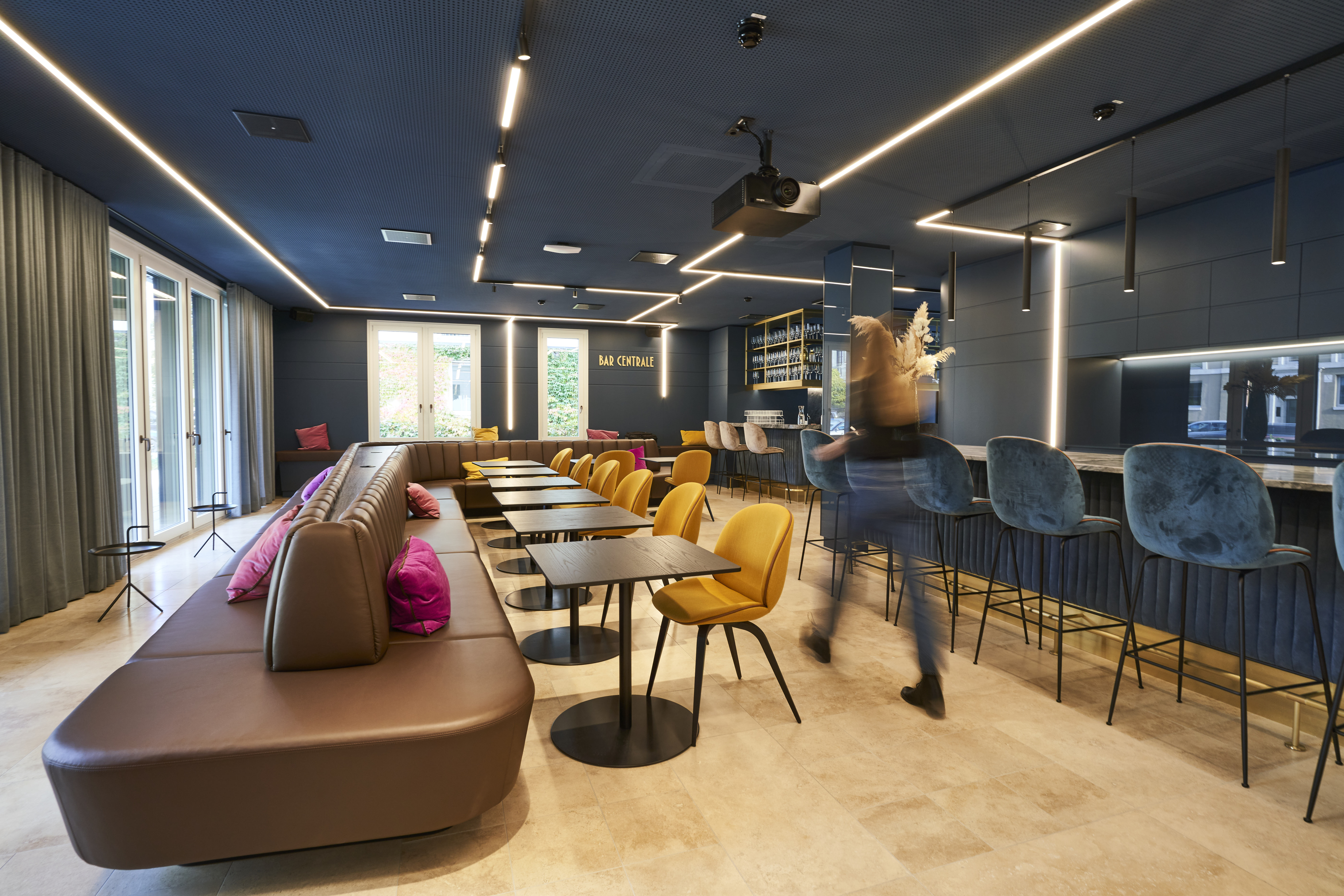 Modern consulting office lounge with sofas, chairs and a person walking symbolising teamwork and dynamic business environment
