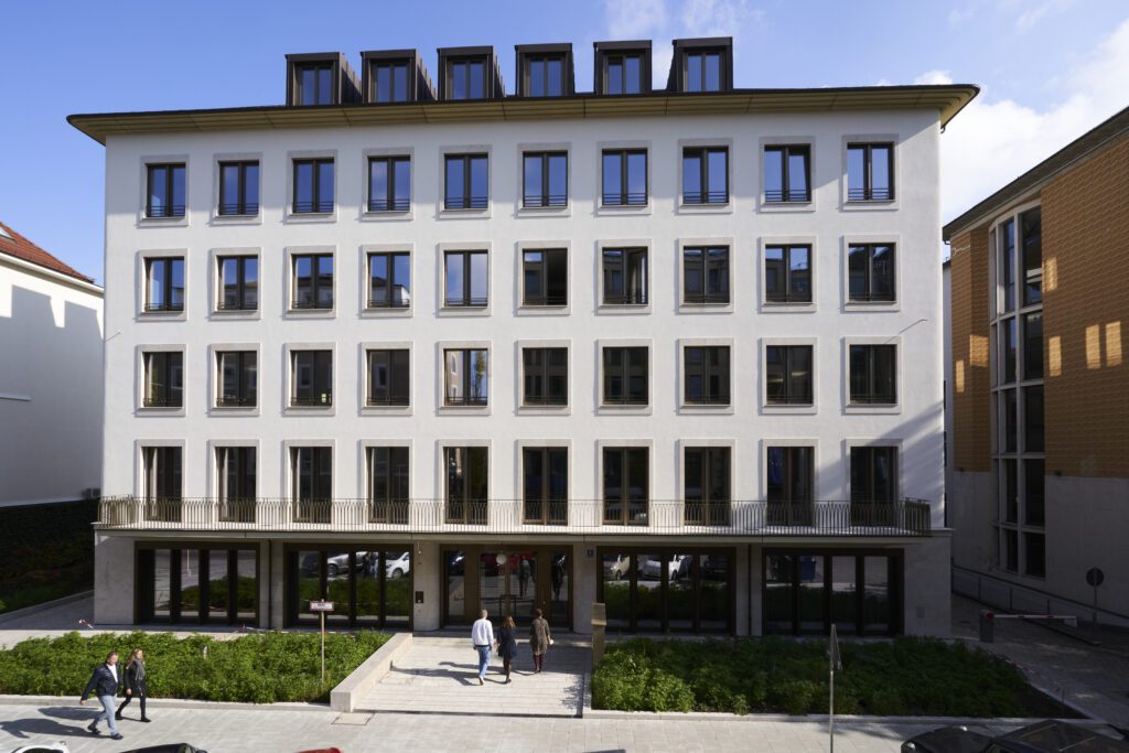 Facade of modern consulting office building with multiple windows and people walking in front representing corporate headquarters