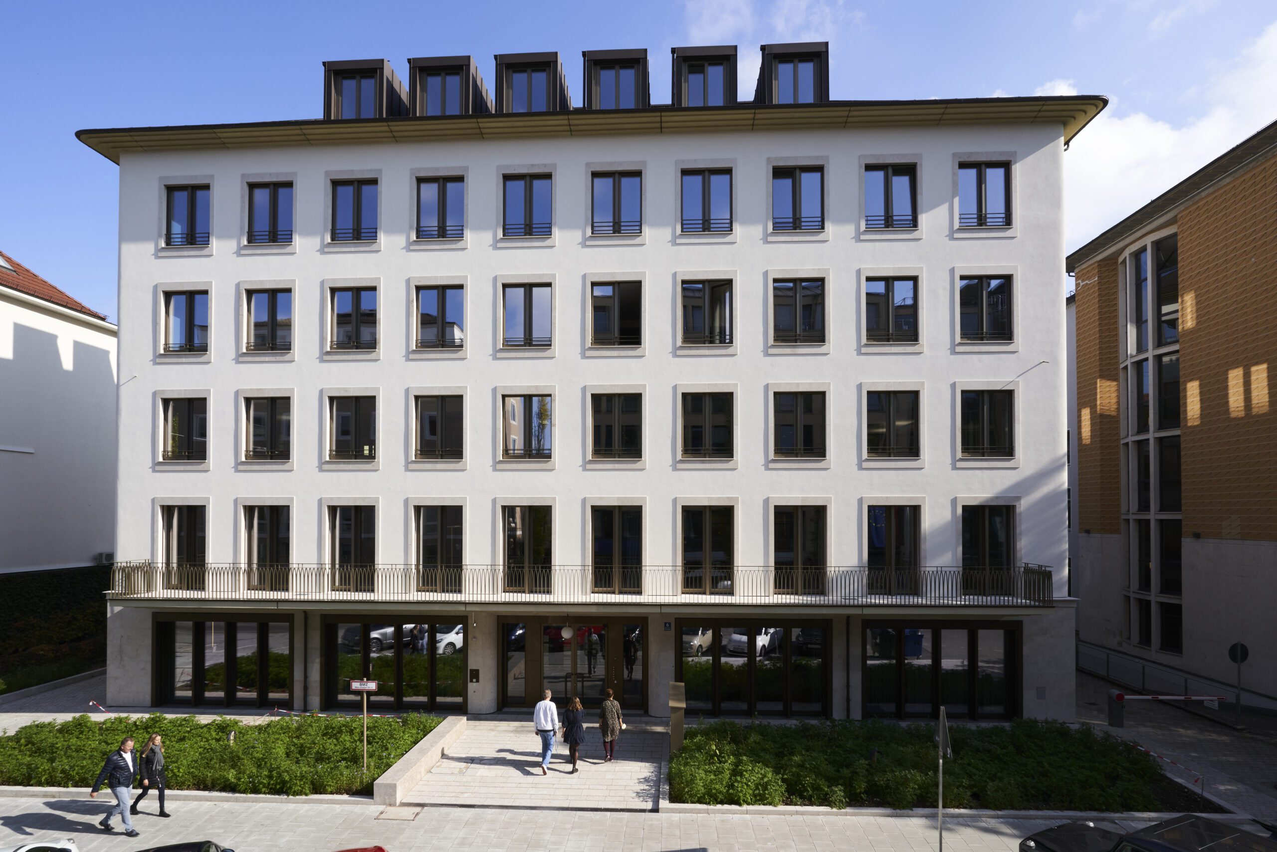 Facade of modern consulting office building with multiple windows and people walking in front representing corporate headquarters
