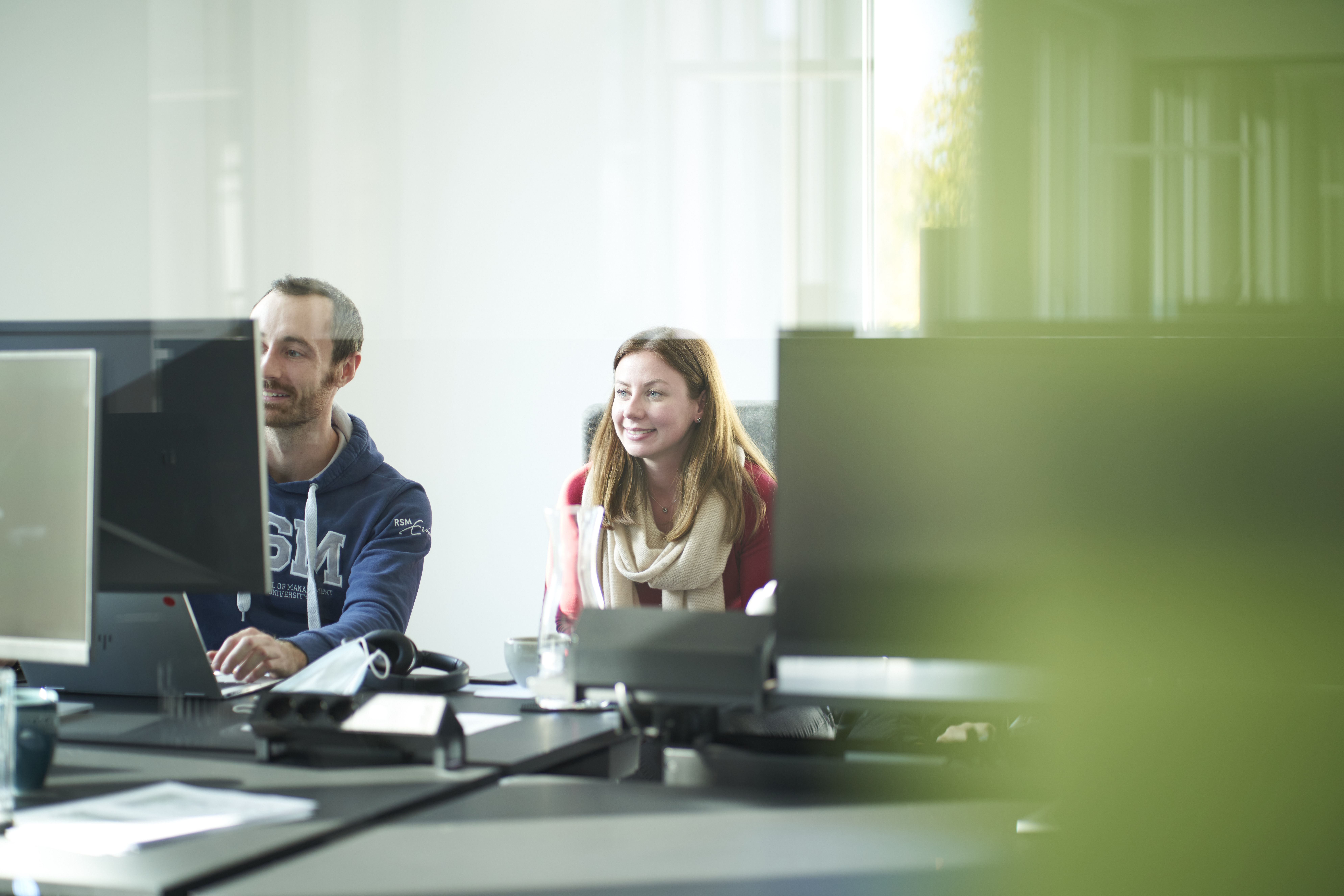 Male and female colleagues collaborating at computers in a modern office environment for business consulting project