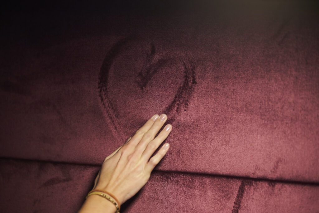 Hand gently touching a textured red surface with a heart drawn, symbolizing empathy, collaboration and client-centric consulting