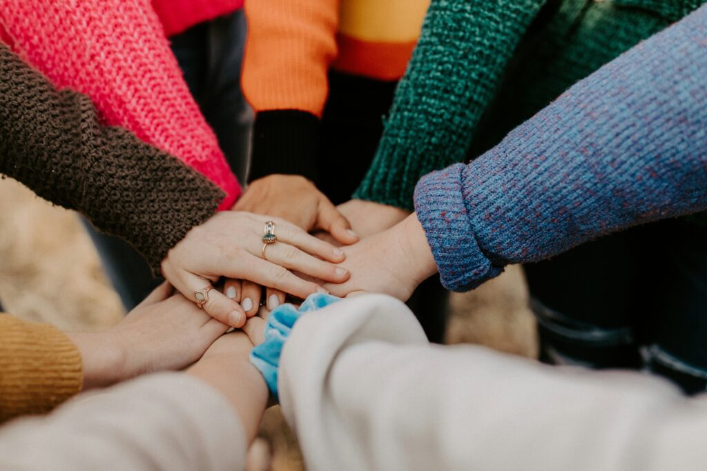 Close-up of diverse colleagues placing their hands together in a group huddle to symbolize teamwork and solidarity during a consulting project.