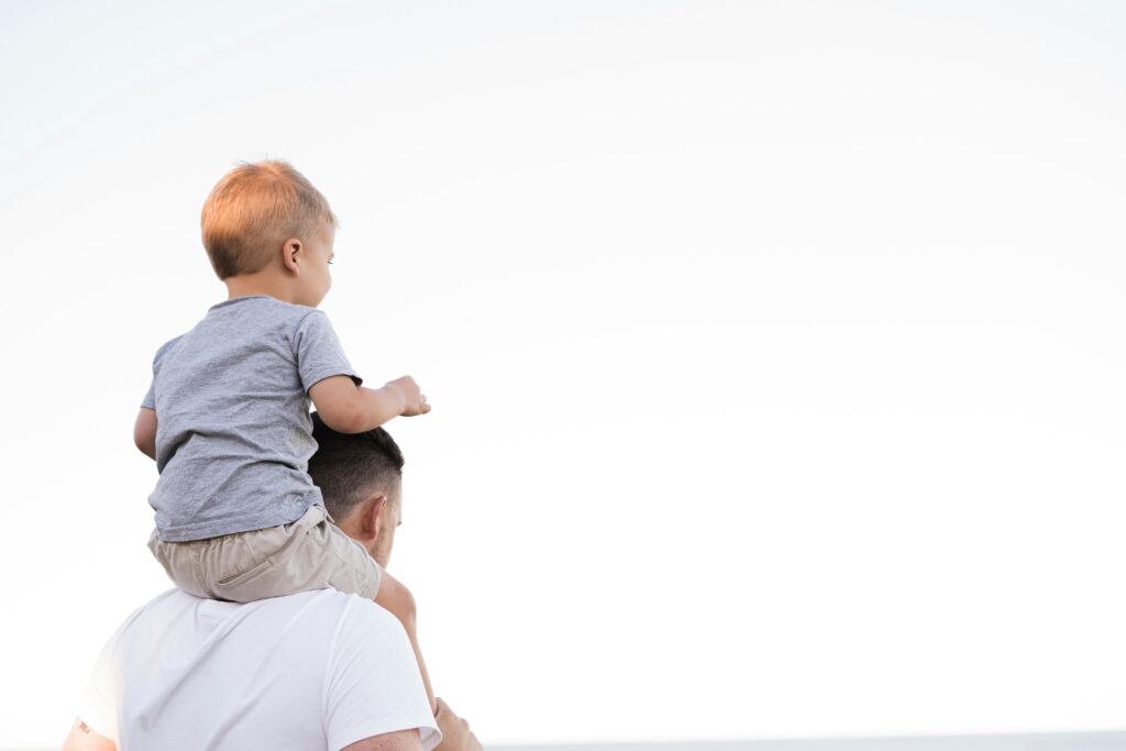 Father carrying young child on his shoulders, symbolising family support and work-life balance values championed by our consulting firm