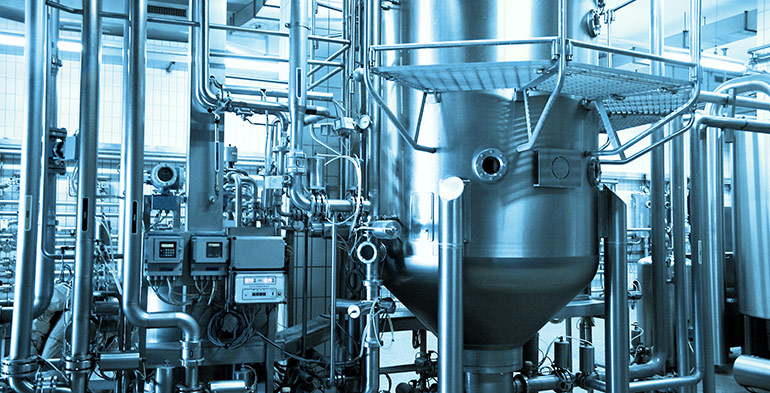 Industrial stainless steel equipment and vessels in a manufacturing plant representing process optimization and restructuring consulting in manufacturing.