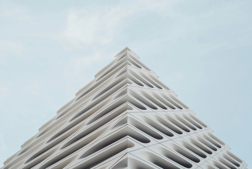 Modern angular building with layered triangular floors against a blue sky representing innovative urban architecture and forward-thinking real estate consulting.