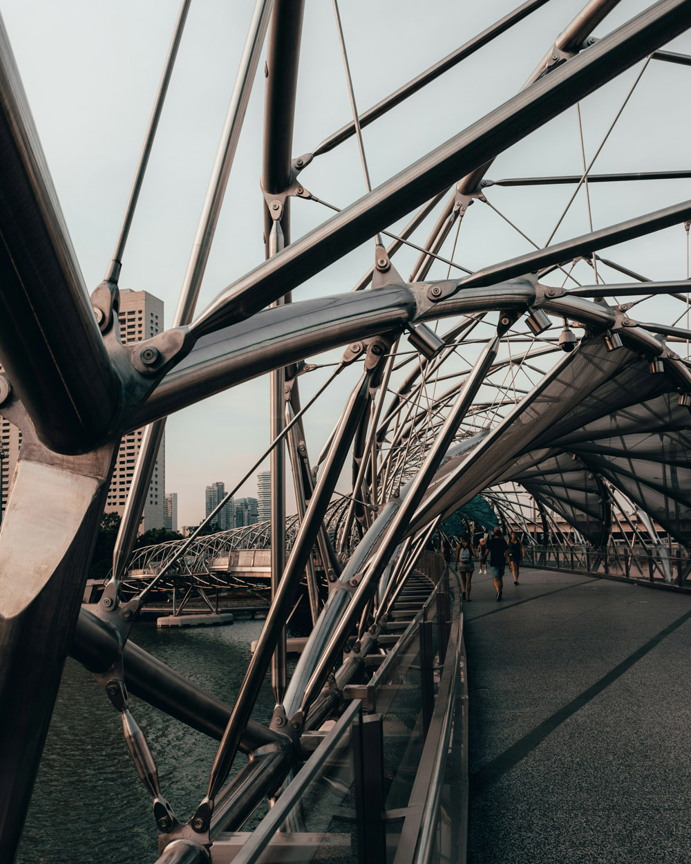 Modern steel pedestrian bridge with intricate structural beams leading into a city skyline, representing connectivity and innovative infrastructure in consulting.