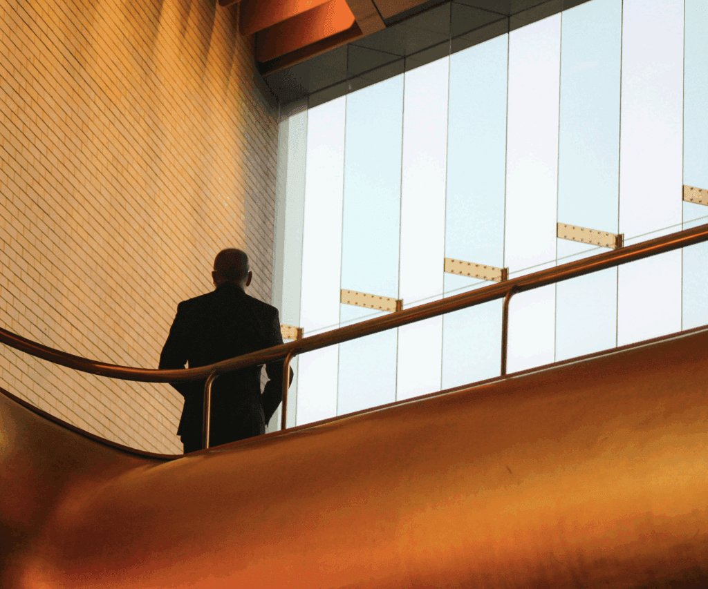 Silhouette of a man ascending an escalator in a modern office building | H&Z