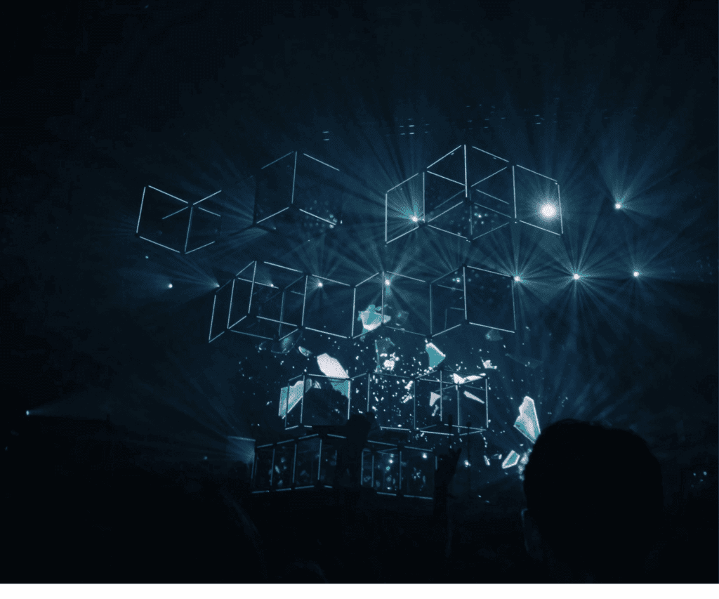 Digital 3D cubes floating above a stage illuminated with blue lights during an event, symbolizing innovative technology and immersive experiences in modern business consulting.