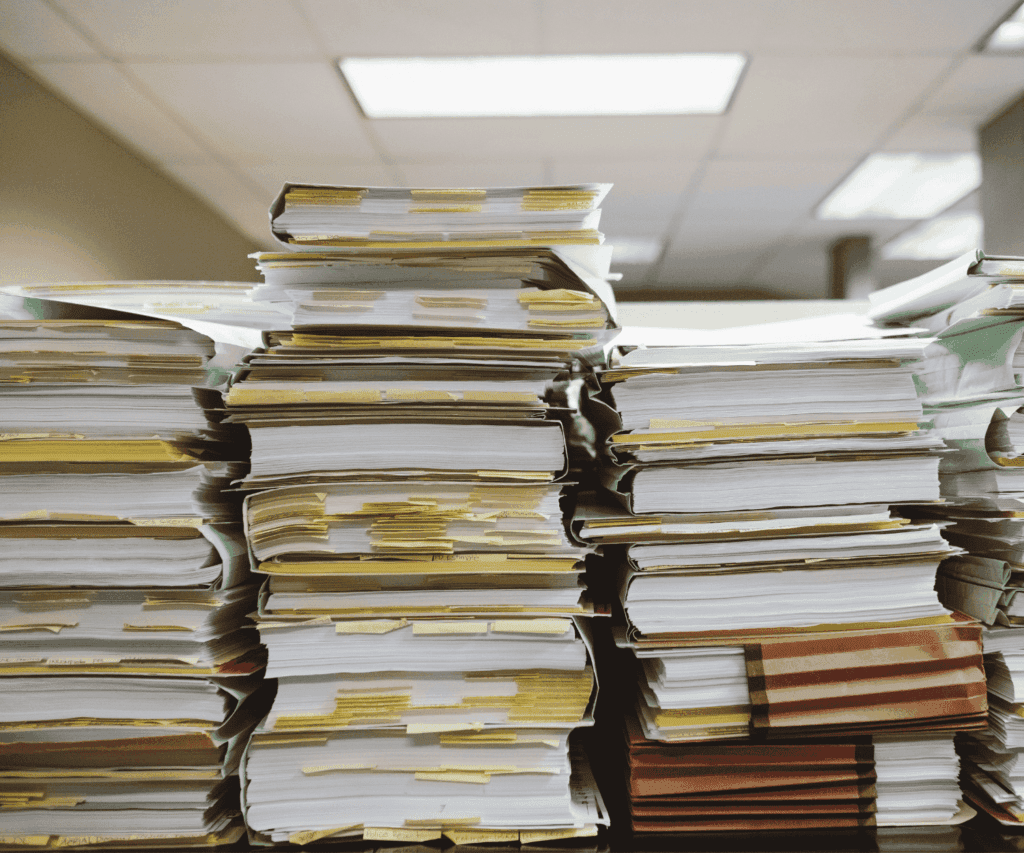 Stack of paperwork and folders representing heavy documentation and the need for efficient document management in consulting projects.