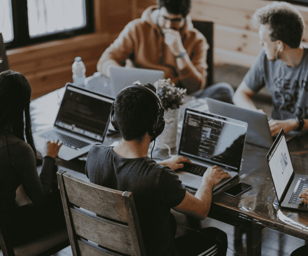 Brainstorming session in an office where a group of professionals collaborate around laptops, representing agile project work and digital collaboration in consulting.