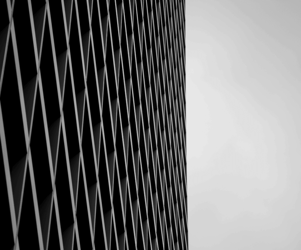 Abstract architectural facade with crisscrossing diamond-shaped pattern in black and grey, representing modern design and structural efficiency, symbolizing precision in consulting.