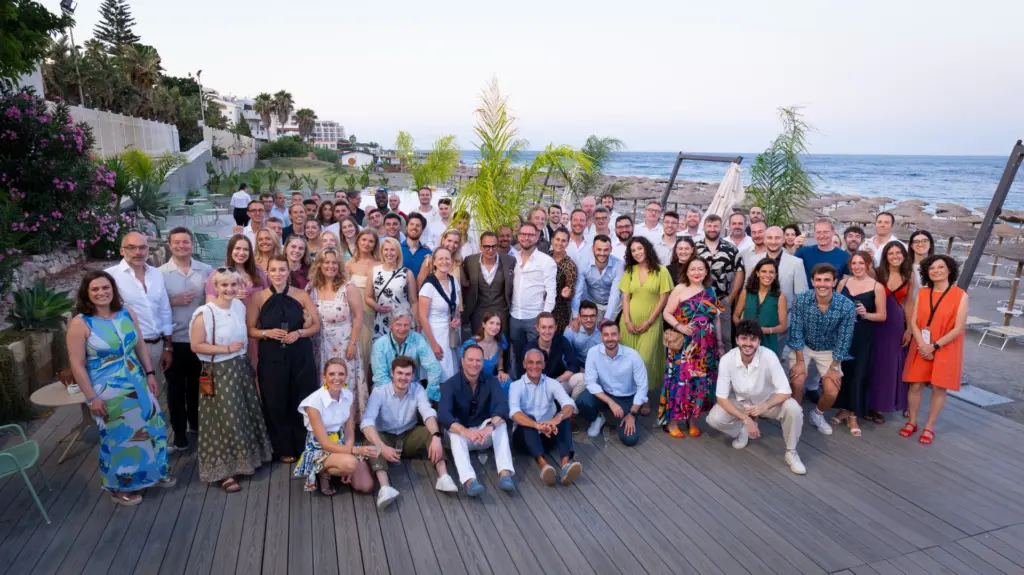 Large group of diverse professionals gathering outdoors at a corporate event, representing team collaboration in consulting services