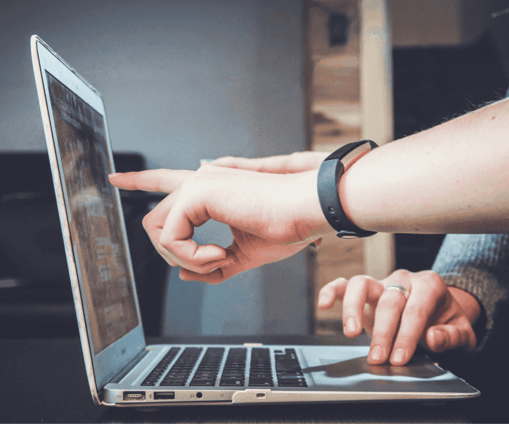 Close-up of hands working together at a laptop, pointing at the screen, symbolizing collaborative digital consulting and teamwork.
