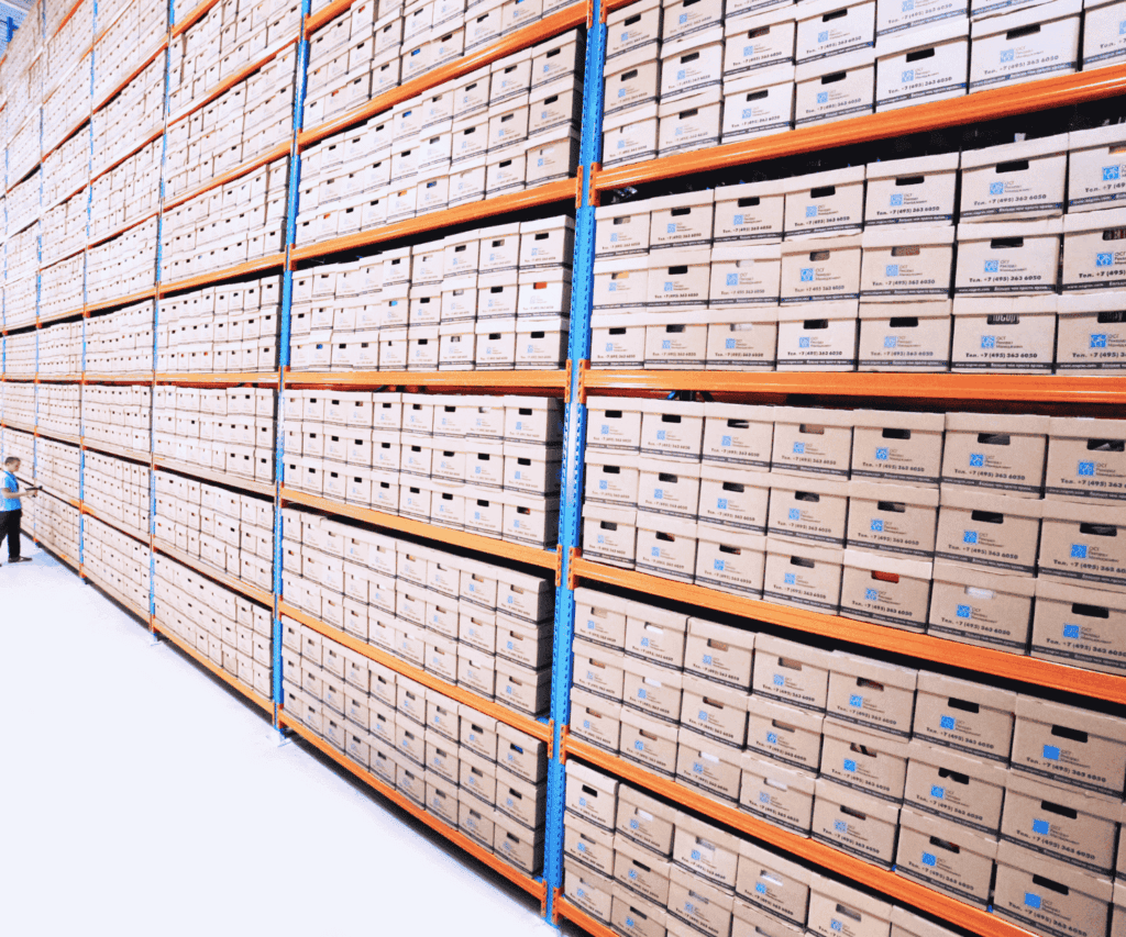 Large wall of shelves filled with neatly stacked archival boxes in a warehouse, highlighting organized logistics and operational efficiency for our consulting services.