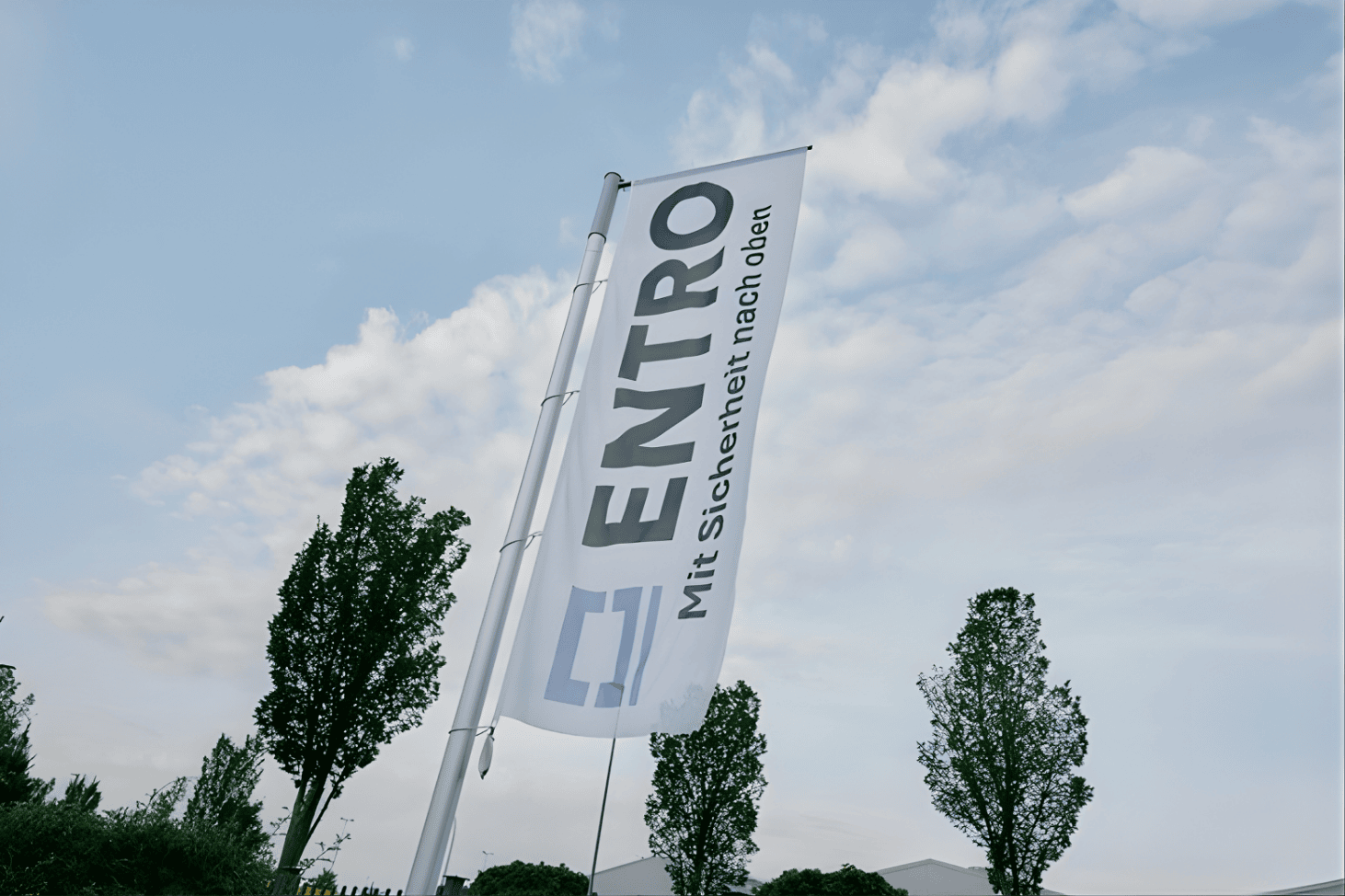ENTRO company flag with slogan 'Mit Sicherheit nach oben' flying against the sky, symbolizing secure upward growth and professional consulting services.