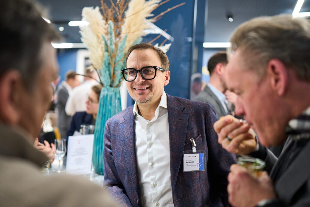 Businessman in a blue blazer chatting at a networking event with pampas grass decor | H&Z
