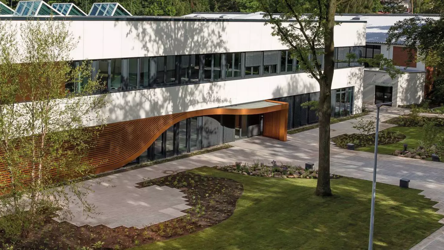 Exterior view of the HARTING office building with a curved wood-panelled entrance canopy | H&Z