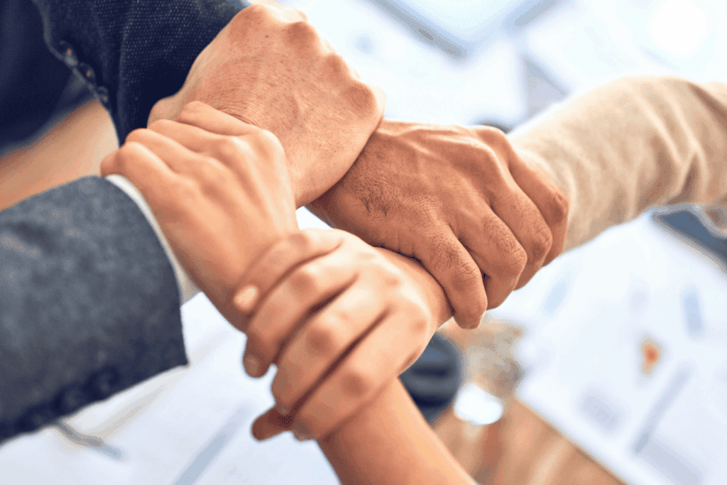 Four hands interlocked in a circle, symbolising teamwork and close collaboration | H&Z