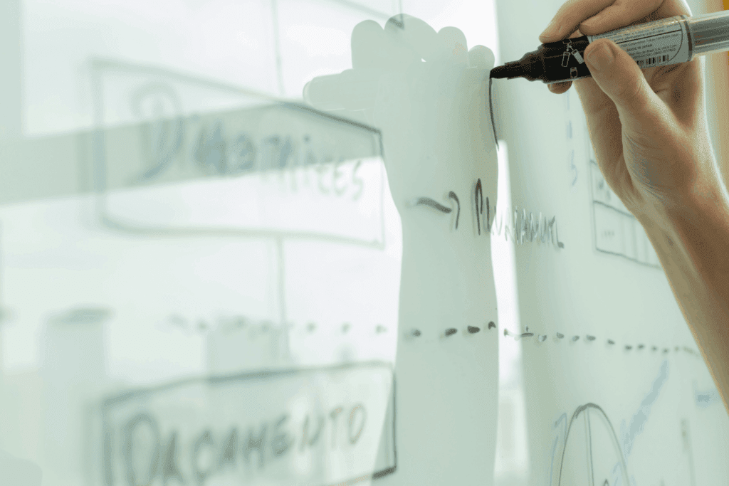 Consultant sketching business diagrams on a whiteboard during a strategy session | H&Z