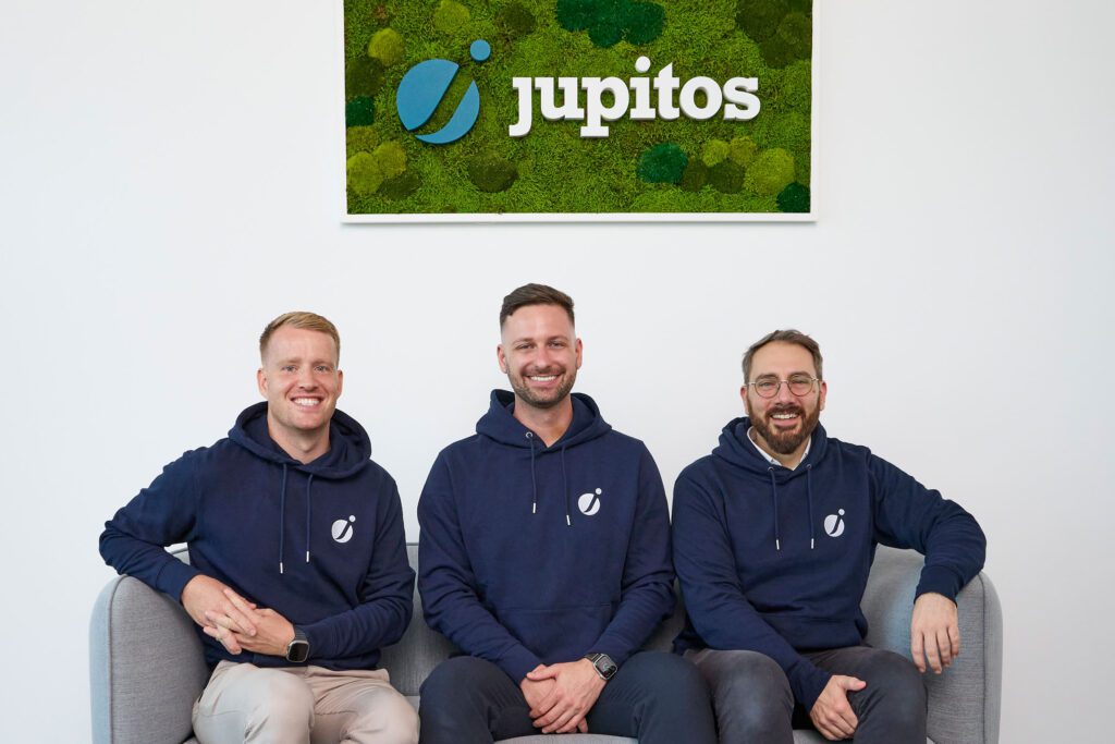 jupitos team sitting with jupitos logo on the wall behind