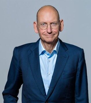 Studio portrait of Daniel Stelter in a navy blazer over a light blue shirt | H&Z