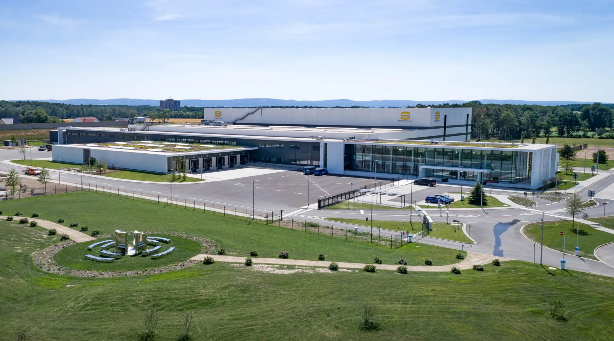 Aerial view of the HARTING company campus with modern office and logistics buildings surrounded by green landscaping | H&Z