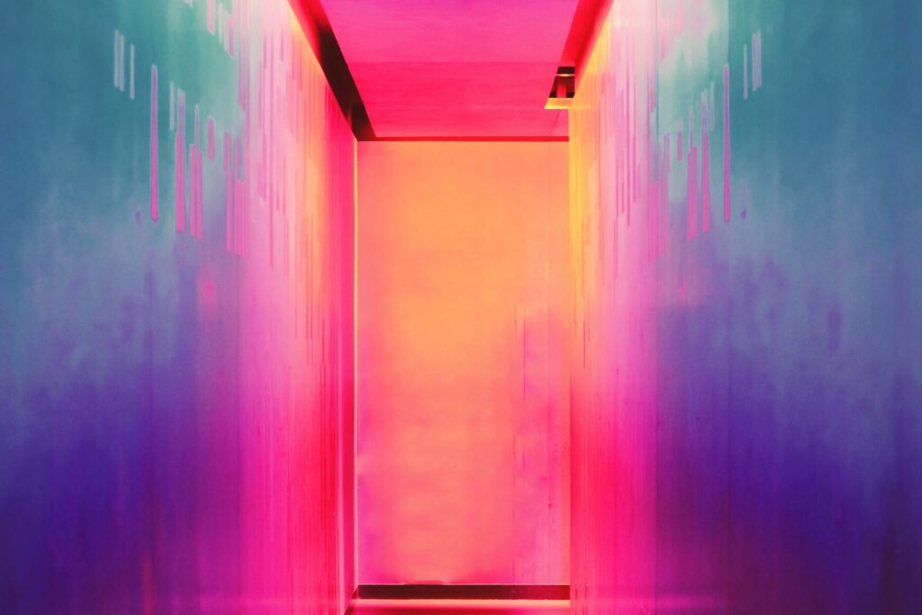 Corridor illuminated in pink, orange and turquoise light with abstract data patterns on the walls