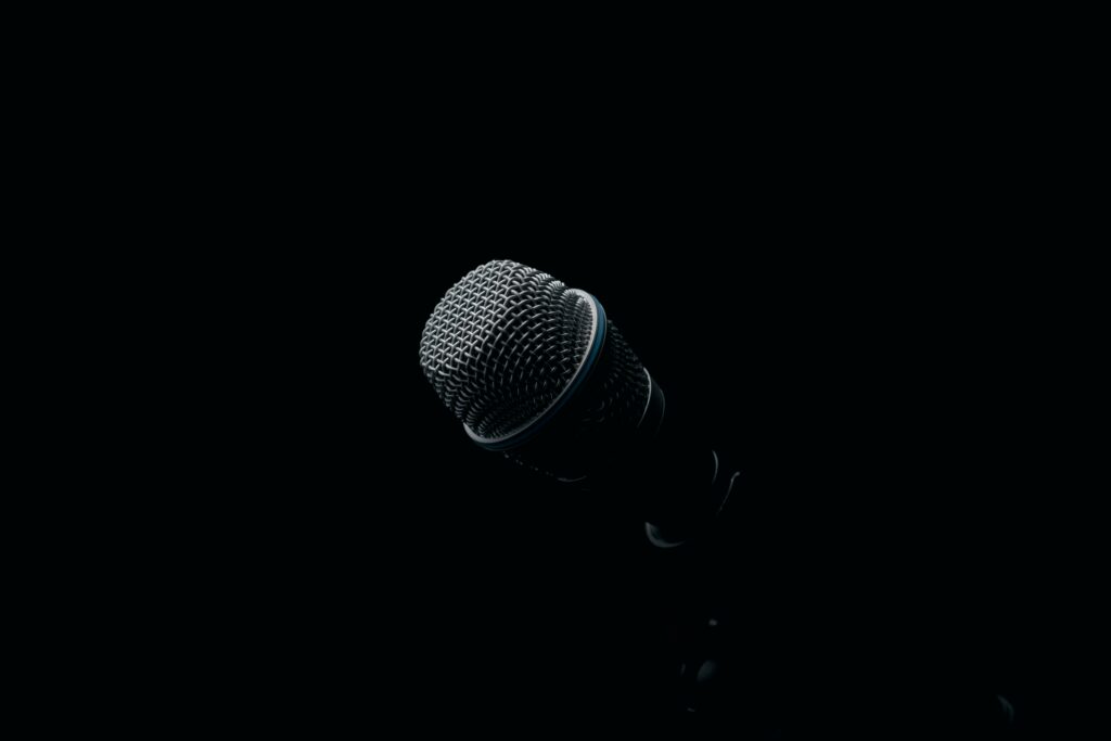 Close-up of a microphone in dramatic low light against a black background | H&Z